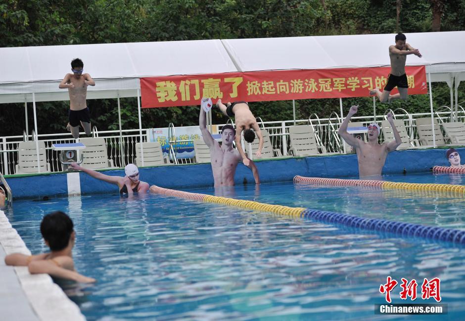 市民正在练习跳水动作。 陈超 摄 8月10日,重庆洋人街一游泳池挂起孙杨、宁泽涛等中国游泳名将的照片,鼓励前来游泳健身的市民向游泳冠军学习。图为游泳池挂起孙杨、宁泽涛等中国游泳队运动员的照片。陈超摄